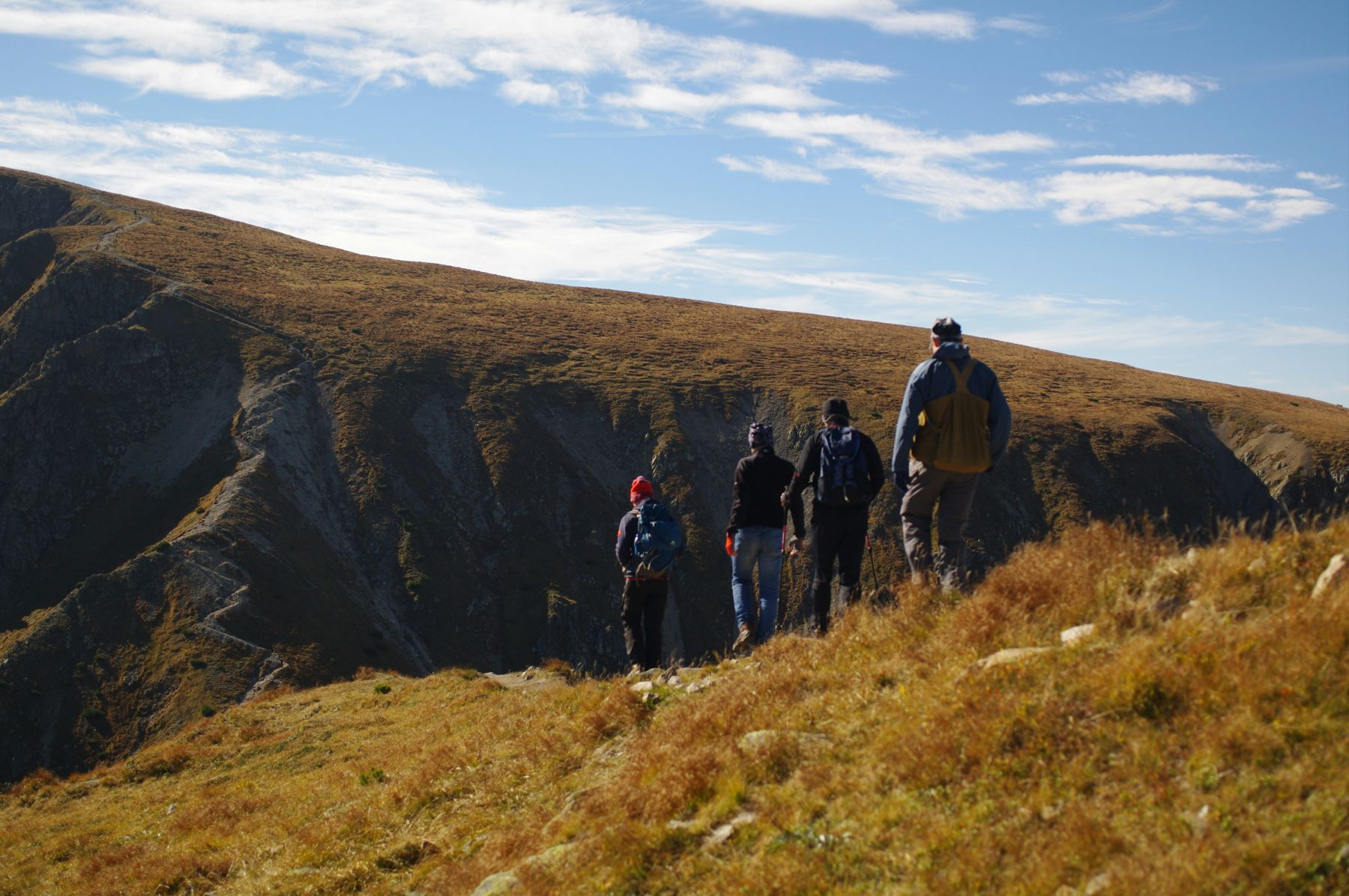 A group of men hiking along a grassy ridge