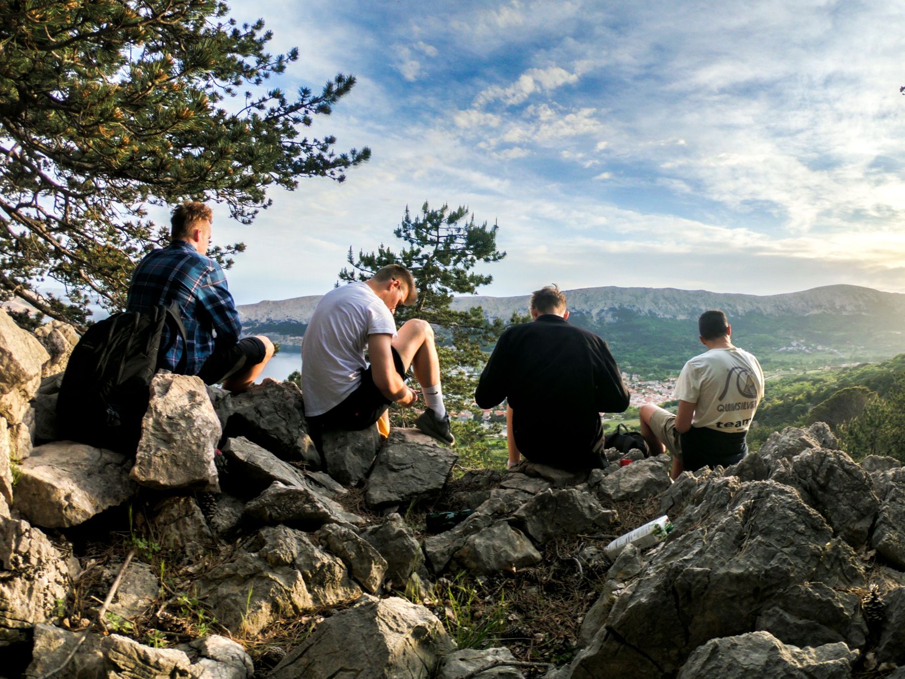 Four men resting on a rocky summit overlooking a valley